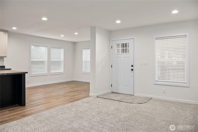 foyer entrance featuring light carpet, baseboards, and recessed lighting