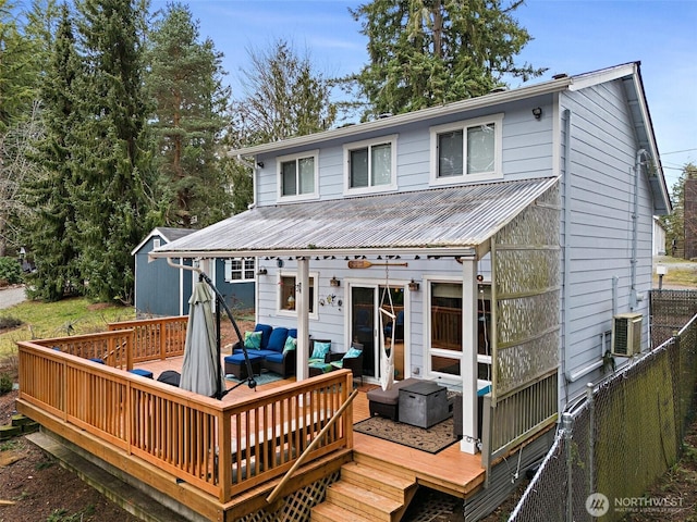 exterior space featuring a deck, metal roof, outdoor lounge area, and fence