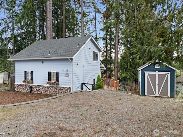 view of home's exterior featuring an outbuilding, a shed, and a shingled roof