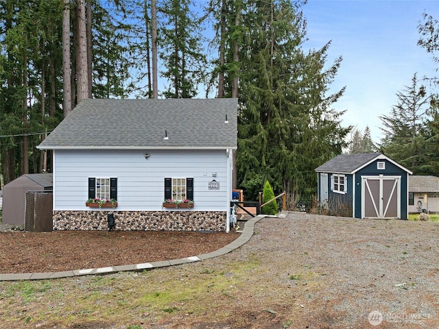 view of front of home featuring an outbuilding, a storage unit, and a shingled roof