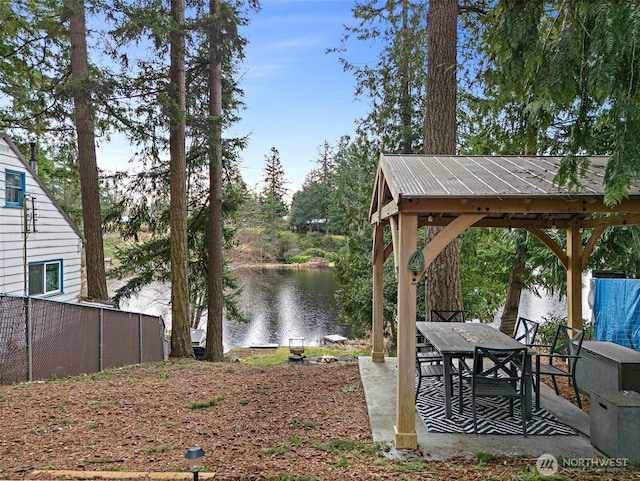 view of yard featuring a water view, fence, outdoor dining area, and a gazebo