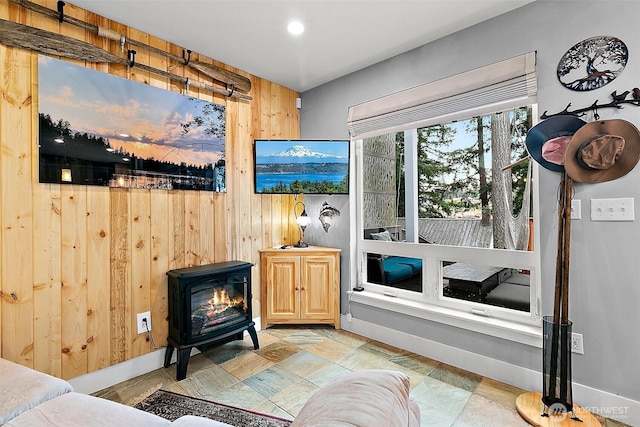 interior space featuring a wood stove, wooden walls, and baseboards