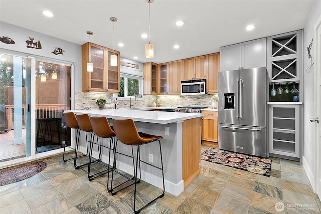 kitchen with decorative backsplash, glass insert cabinets, a breakfast bar, a peninsula, and stainless steel appliances