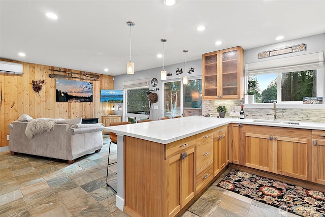 kitchen featuring a wall unit AC, a breakfast bar area, backsplash, open floor plan, and a sink