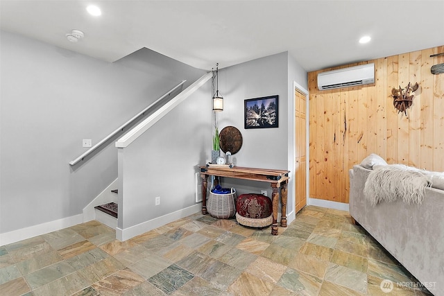 interior space featuring wooden walls, baseboards, a wall unit AC, stone finish floor, and recessed lighting