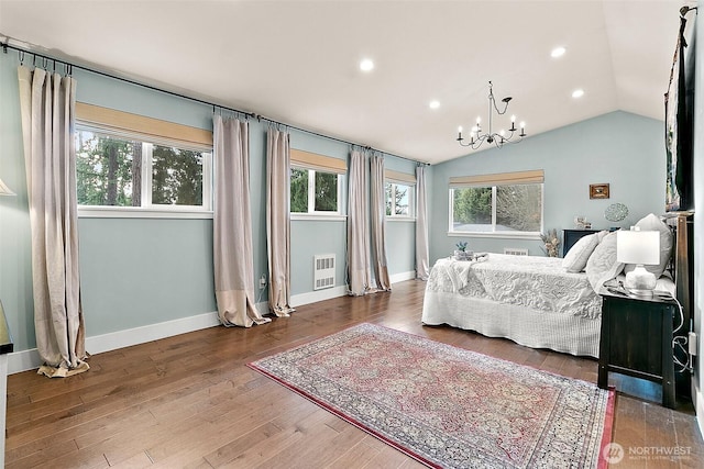 bedroom with lofted ceiling, multiple windows, a chandelier, and wood finished floors