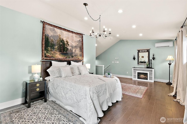 bedroom with baseboards, wood finished floors, vaulted ceiling, a chandelier, and a wall mounted AC