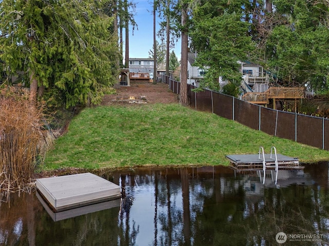 view of dock featuring a water view, fence, and a lawn