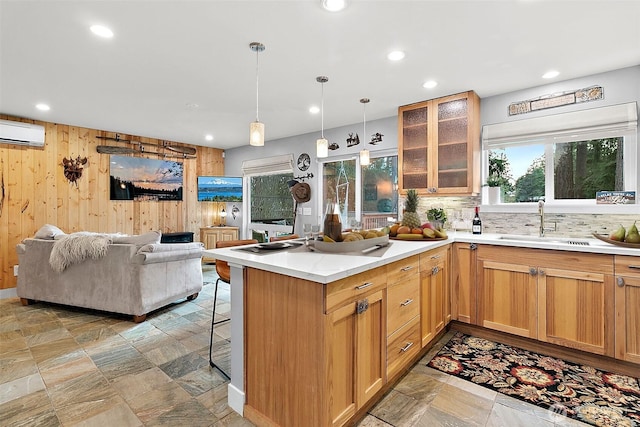 kitchen with a peninsula, a sink, a kitchen breakfast bar, open floor plan, and a wall mounted AC