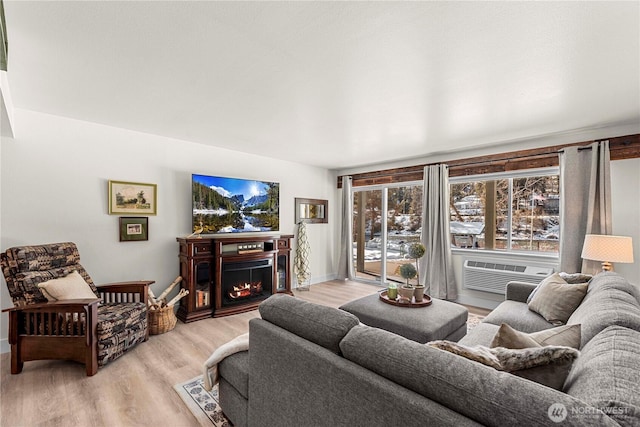 living room with light wood-style floors, a warm lit fireplace, and baseboards