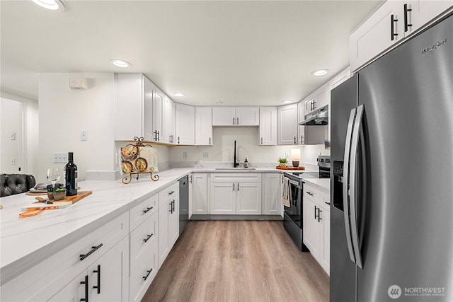 kitchen with appliances with stainless steel finishes, white cabinetry, a sink, light stone countertops, and under cabinet range hood