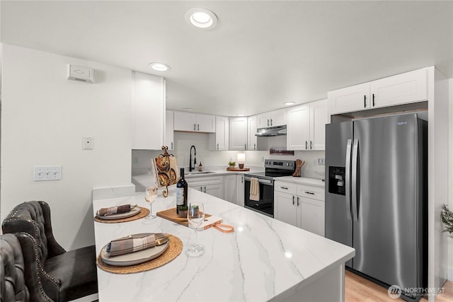 kitchen featuring light stone counters, appliances with stainless steel finishes, white cabinets, a sink, and under cabinet range hood