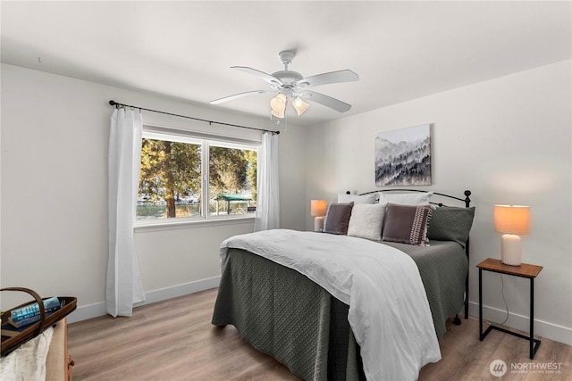 bedroom with light wood-style floors, baseboards, and a ceiling fan