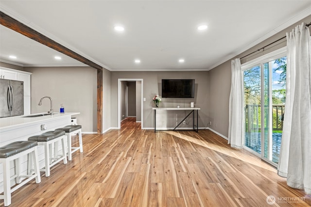 living area with light wood-style flooring, baseboards, and crown molding