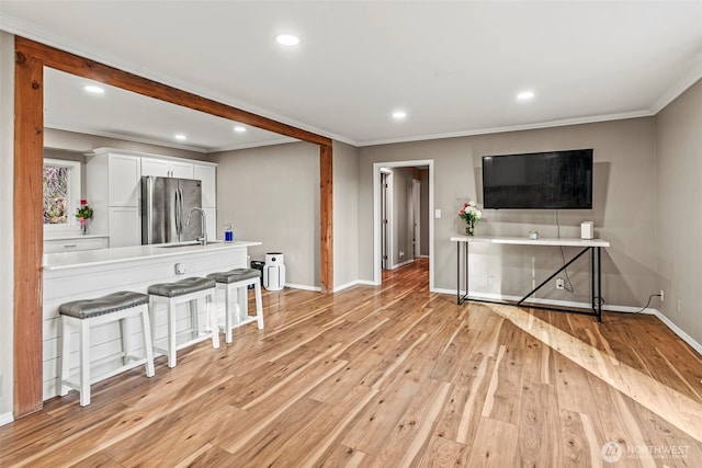 living room featuring ornamental molding, light wood finished floors, recessed lighting, and baseboards