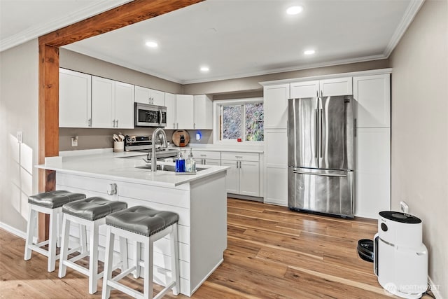 kitchen with appliances with stainless steel finishes, light countertops, white cabinetry, and a breakfast bar area