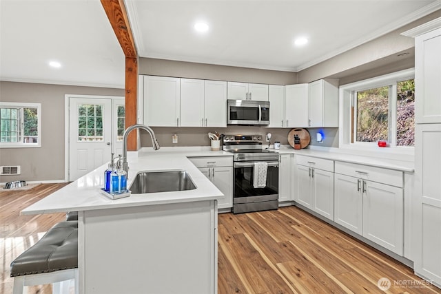 kitchen with a breakfast bar area, appliances with stainless steel finishes, light countertops, and a sink