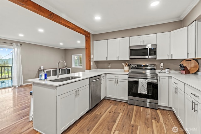 kitchen featuring stainless steel appliances, a peninsula, light countertops, and white cabinetry