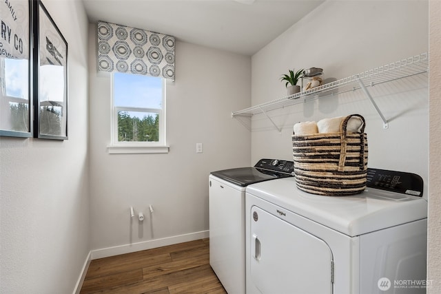 laundry area with baseboards, laundry area, wood finished floors, and washer and dryer