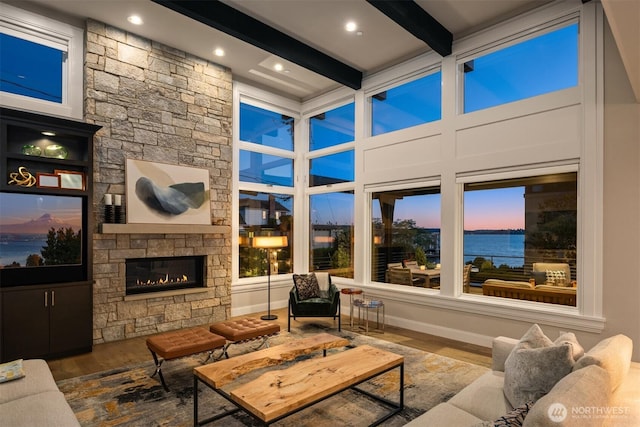 sunroom with a water view, beamed ceiling, and a fireplace