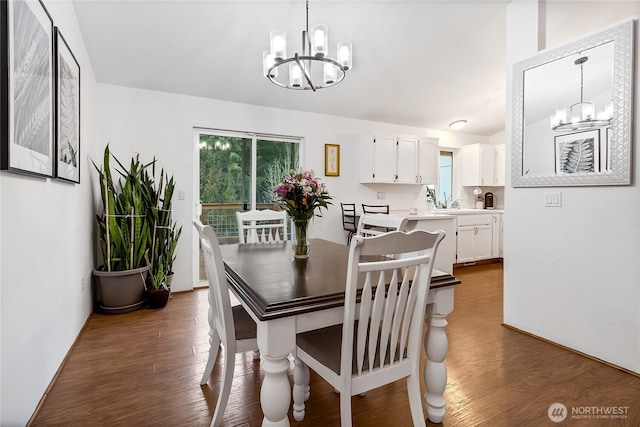 dining area with dark wood-style floors and a notable chandelier