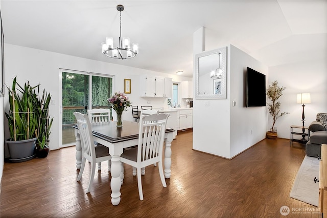 dining area with a chandelier, a wealth of natural light, dark wood-style flooring, and vaulted ceiling