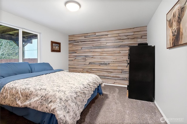 carpeted bedroom with baseboards, an accent wall, and wooden walls