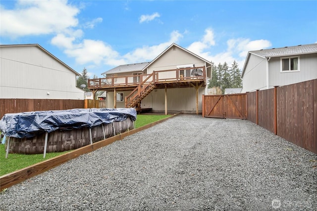 back of house featuring stairs, fence, a deck, and a fenced in pool