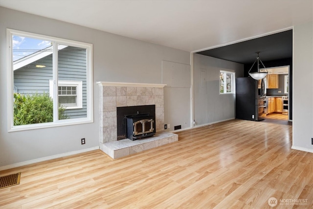 unfurnished living room featuring light wood-style floors, a healthy amount of sunlight, and visible vents