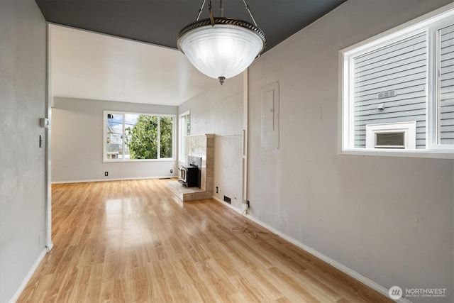 unfurnished living room featuring light wood finished floors, electric panel, and baseboards