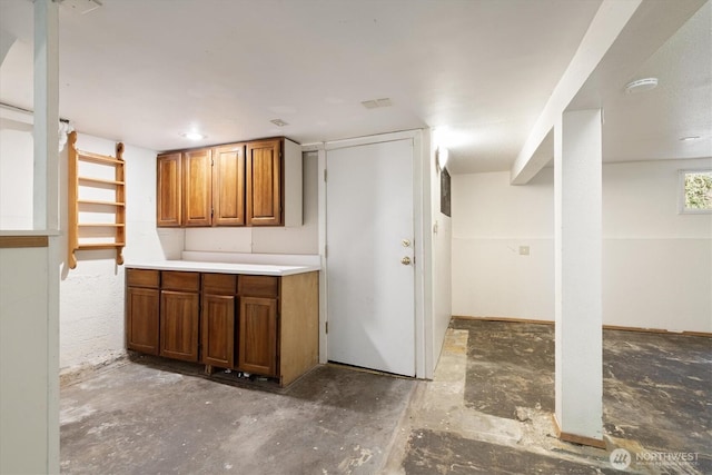 kitchen with light countertops, brown cabinets, and unfinished concrete flooring