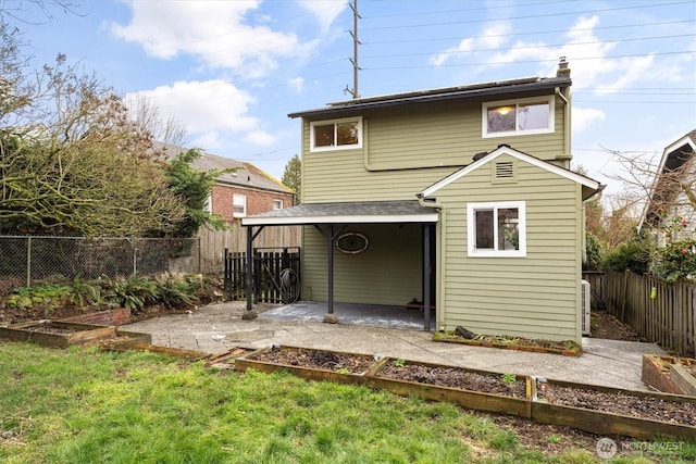 rear view of house featuring a patio area, a garden, a lawn, and a fenced backyard