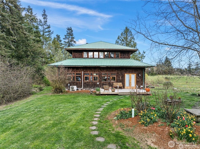 back of property featuring a standing seam roof, metal roof, a lawn, and a wooden deck