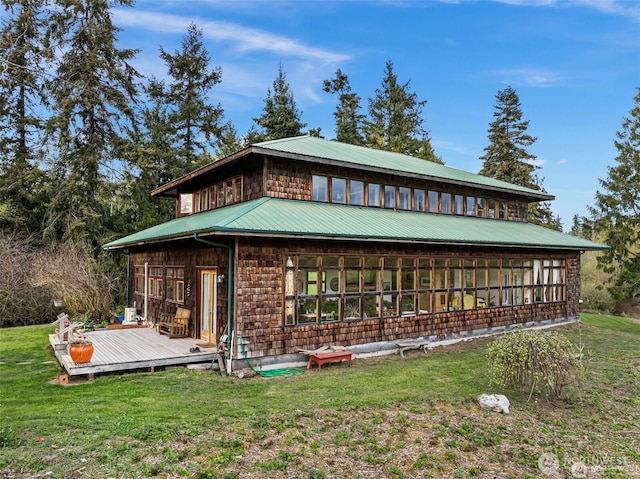 view of front of home featuring metal roof, a front lawn, and a wooden deck