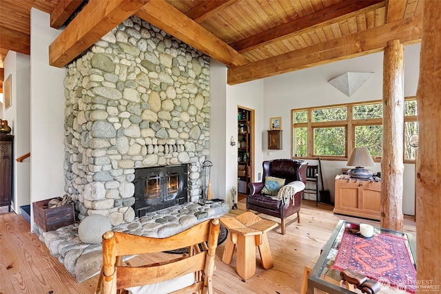 living room featuring wooden ceiling, beamed ceiling, a stone fireplace, and wood finished floors