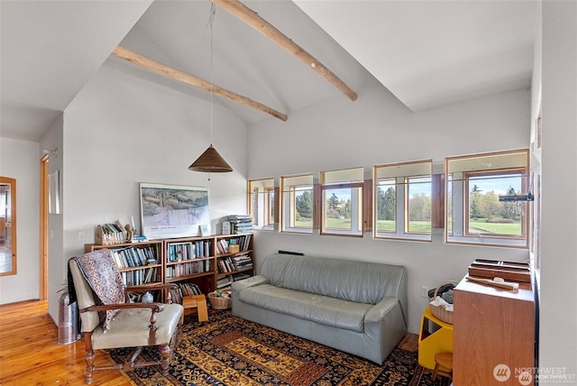 living area featuring high vaulted ceiling, beam ceiling, and wood finished floors