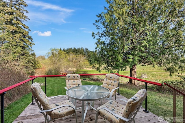 wooden terrace with outdoor dining area and a lawn