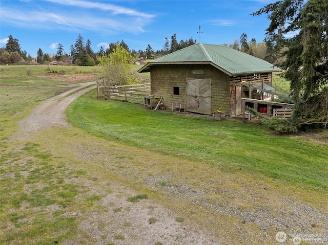 view of side of home with a yard, fence, metal roof, and an outbuilding