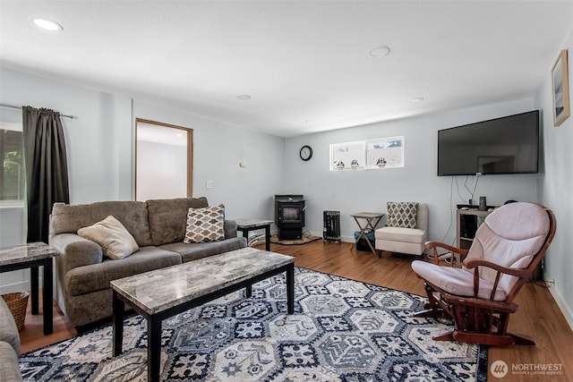 living room with a wood stove, baseboards, and wood finished floors