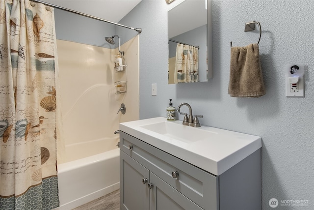 bathroom with a textured wall, shower / tub combo, and vanity