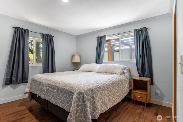 bedroom featuring ornamental molding, dark wood-style flooring, and baseboards