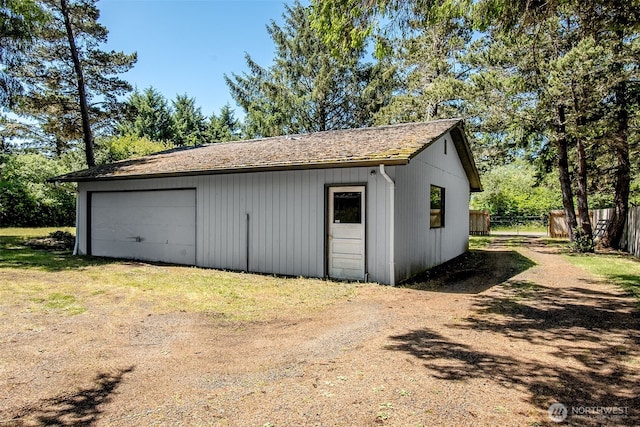 view of outdoor structure with driveway, an outdoor structure, and fence