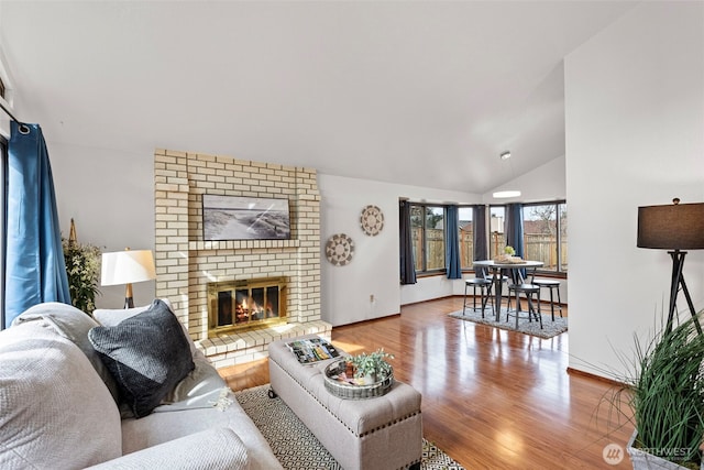 living area with a fireplace, lofted ceiling, wood finished floors, and baseboards