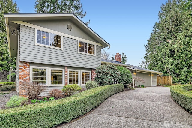 view of front of house with a garage, driveway, brick siding, and fence