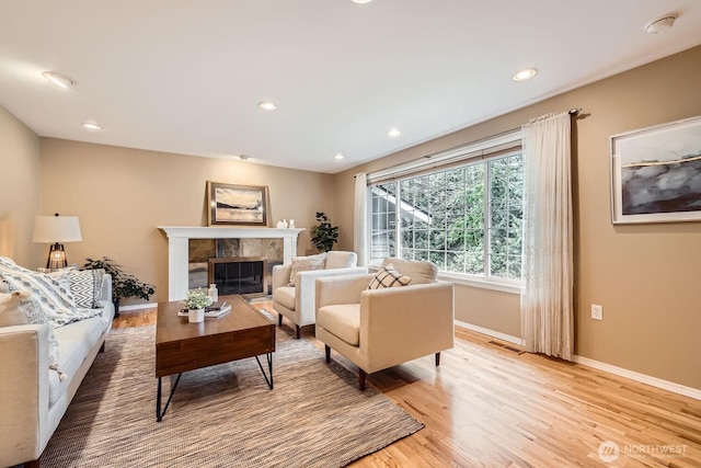 living area featuring light wood-type flooring, a fireplace, baseboards, and recessed lighting