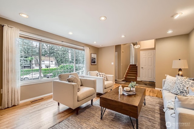 living area featuring light wood finished floors, baseboards, visible vents, stairs, and recessed lighting