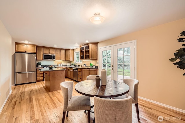 dining room with light wood finished floors, baseboards, and french doors