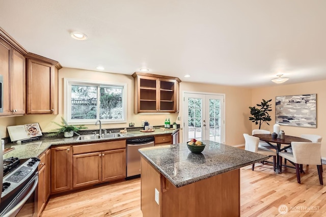 kitchen with appliances with stainless steel finishes, light wood-type flooring, french doors, and a sink