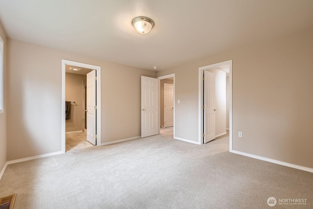 unfurnished bedroom featuring visible vents, ensuite bath, light carpet, and baseboards