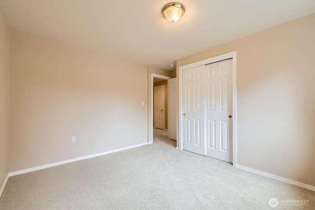 unfurnished bedroom featuring baseboards, a closet, and light colored carpet